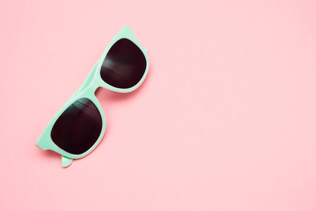Green pastel sunglasses isolated on punchy pink background, top view. Copy space. Summer concept.の写真素材
