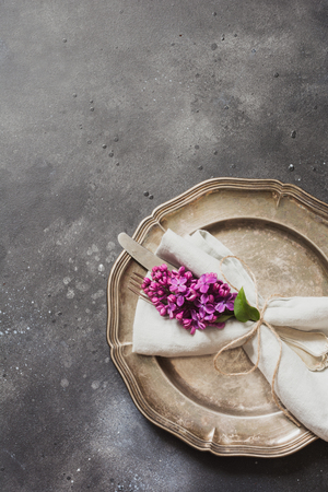 Spring elegant table place setting with violet lilac flowers, silverware on vintage table. Top view.の写真素材
