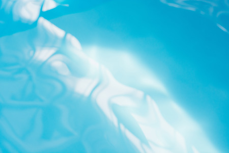 Blue pool water with sun reflections. Abstract blurred pattern. Background.