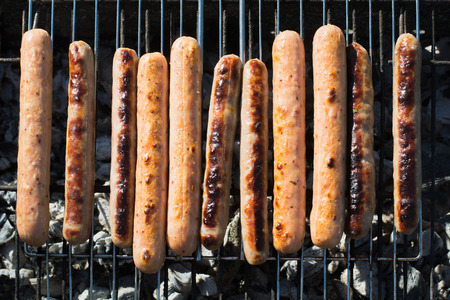 Spicy sausages grilling on portable barbecue on summer picnic. Outdoors. Smoke and fire. Top view.の写真素材