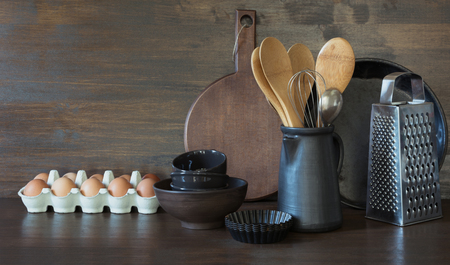 Crockery, clayware, dark utensils and other different stuff on wooden tabletop. Kitchen still life as background for design. Copy space.の写真素材
