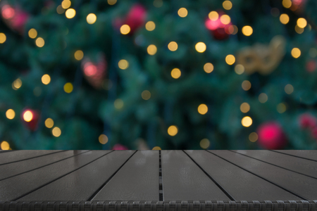 Wooden dark tabletop and blurred christmas tree bokeh. Xmas background for display your products.の写真素材