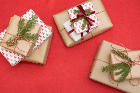 Christmas gift box wrapped in ornament paper and decorative red rope ribbon on red surface. Creative...