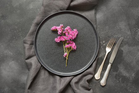 Elegance place setting with pink wildflowers on black table. Top view.の写真素材