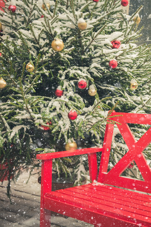 Traditional decorative red bench for relaxing in a city fair. Night light. Christmas. Snowy.の写真素材