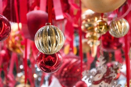 Christmas red and golden balls hanging on red ribbons in fair kiosk for workshop and sale handcrafted xmas gifts. Outdoors. Close up.の写真素材