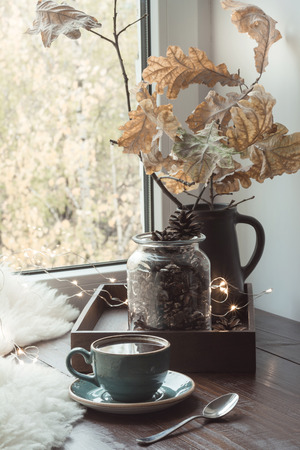 Still life in home interior. Cozy winter or autumn cup of coffee at home warm fluffy furskin, garland, swedish hygge concept.の写真素材