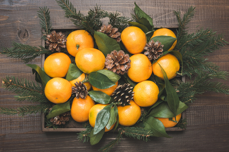 Fresh mandarins with leaves in box on wooden table. Christmas composition. Holiday Centerpieces.の写真素材