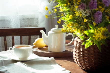 Early morning with cup of tea and fresh wild flowers in basket. Rustic farmhouse.の写真素材