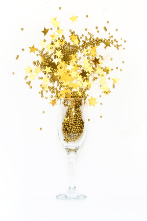 Golden confetti in shape of stars poured out glasses of champagne. Top view. Christmas party. Magic night.の写真素材