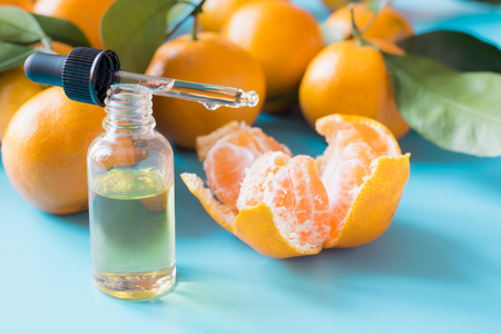 Essential oil of orange mandarin in glass bottle over pastel blue background. Spa and wellness concept.の写真素材