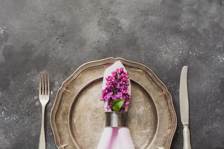 Spring elegant table place setting with violet lilac flowers, silverware on vintage table. Top view.の写真素材
