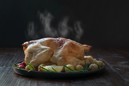 Traditional Christmas roasted chicken with potatoes and rosemary on wooden black table. Close up. Copy space.の写真素材