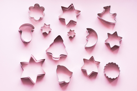 Various Christmas-themed cookie cutters on pastel pink. Holiday card. Top view and flat lay. Xmas pattern.の写真素材