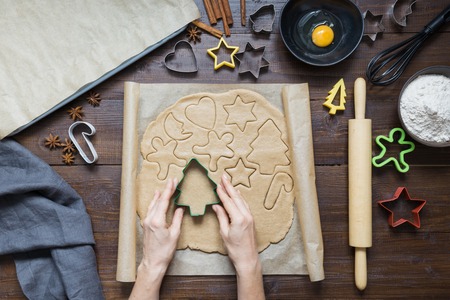 Homemade christmas cookies on parchment. Woman rolls dough. Xmas pattern. The process of baking homemade cookies. Top view.の写真素材