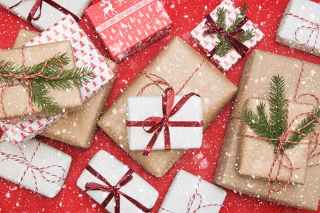 Christmas gift box wrapped in ornament paper and decorative red rope ribbon on red surface. Creative hobby, top view. Prepare to Xmas. Banner.の写真素材