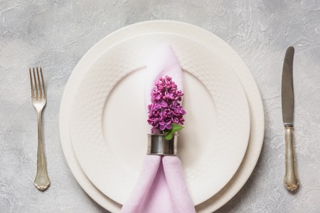 Spring elegant table place setting with lilac flowers, silverware on light background. Top view.の写真素材