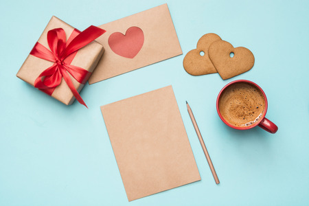 Valentine's day greeting card. Blank for love letter with gift, red hearts, cookies on blue. Top view. Copy space.の写真素材