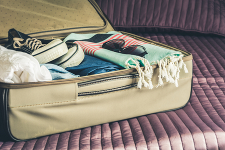 Open suitcase with female clothes for trip vacation. Packing things.の写真素材