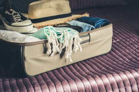 Open suitcase with female clothes for trip vacation on bed. Packing things.の写真素材