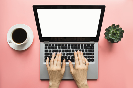 Woman typing by laptop on office pink table. Top view with space for text on screen.の写真素材