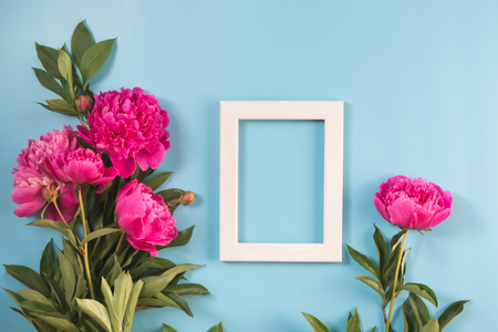Bouquet of beautiful pink peony flowers and white frame for text on punchy pastel blue. Copy space. Top view. Flat lay.の写真素材