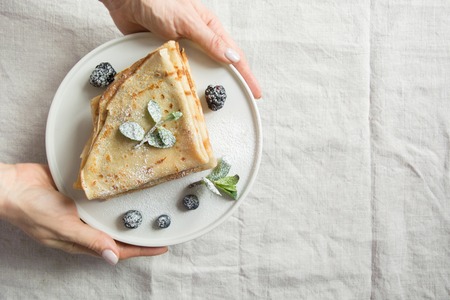 Tasty traditional russian breakfast of pancakes. Russian pancakes in female hand. Top view. Pancake week. Shrovetide.の写真素材
