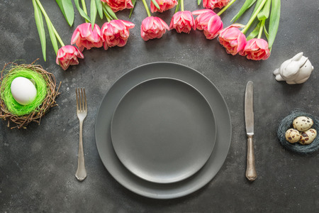 Easter table setting with eggs nest and tulip as decor on dark. Top view. Easter dinner. Top view.の写真素材