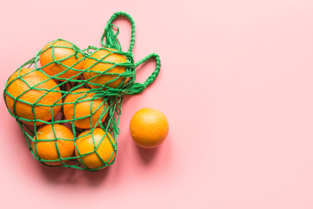 Shopping bag with fresh orange on pink. Zero waste concept. Space for text. View from above.の写真素材