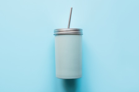 Top view of a reusable jar with a metal lid and a straw for summer drinks. Reusable application....