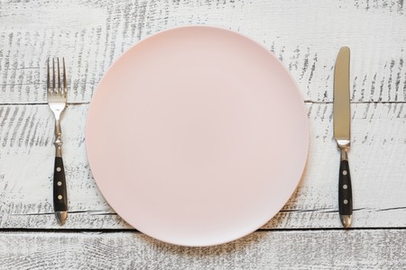 Table place setting with pink plate on white wooden table. View vrom above. Horizontal orientation.の写真素材