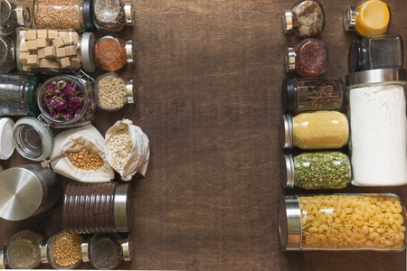 Raw grains, cereals and pasta in glass jars on wooden tabletop. Healthy cooking, clean eating. Space for text. Storage and save. Zero waste concept. View from above.の写真素材