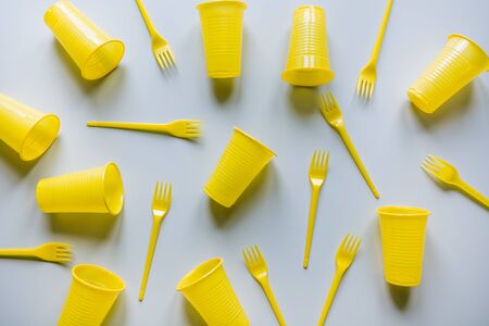 Disposable picnicyellow utensils on grey. Environment eco friendly discarded plastic garbage for recycle concept.Top view. Flat lay. Pattern.の写真素材