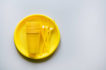 Single use picnic yellow utensils on grey. Environment, eco friendly, plastic garbage for recycle concept. Top view. Space for text. Flat lay.の写真素材