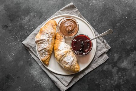 Freshly baked croissants with berry jam on dark gray background. Top view.の写真素材