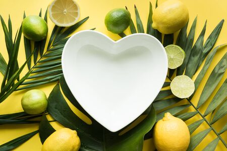 Tropical frame as heart of palm and monstera on yellow. Summer background. Top view, flat lay. Space for text.の写真素材