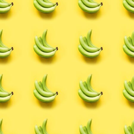 Sweet fresh green banana on punchy pastel yellow background. Top view. Seamless pattern. Square image.の写真素材