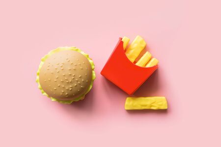 Plastic burger salad, tomato with frying potato on pink background. Horizontal orientation. Children's toy. Concept of harmful artificial food. Plastic. Not organic. Not useful.の写真素材