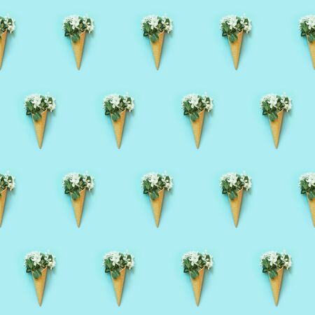Seamless pattern of white spring flowers in waffle cone on blue background. Spring concept. Top...