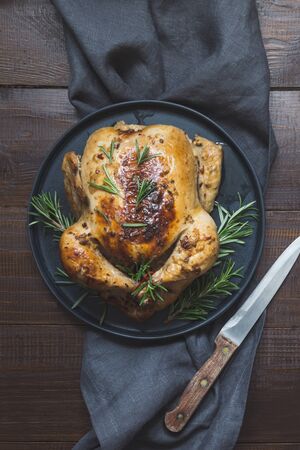 Traditional roasted turkey garnish rosemary on dark wooden table. Top view. Vertical orientation. Thanksgiving day.の写真素材