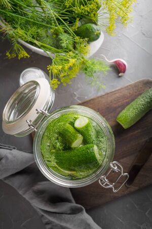 Pickling and fermentation cucumber in glass jar with dill and garlic on dark grey concrete table. Close up. Top view.の写真素材