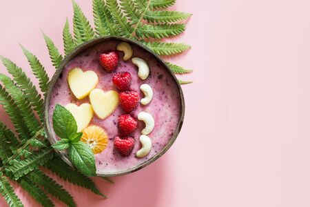 Healthy breakfast banana and blueberry smoothie decorated with fruits in coconut bowl on pink background. View from above. Clean eating, vegetarian food concept.の写真素材