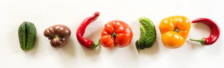 Oddly shaped organic  tomatoes, pepper, cucumber on white concrete with copy space. Concept of organic vegetables.の写真素材