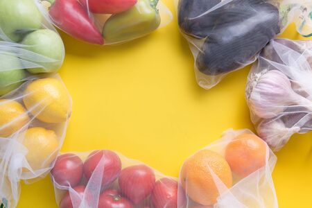 Fruits and summer vegetables in reusable eco friendly mesh bags on bright yellow background. Zero waste shopping. Ecological concept. Stop pollution.の写真素材