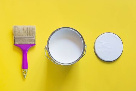 Purple brush with open can of white paint on yellow background. Trend repairs concept. Top view.の写真素材