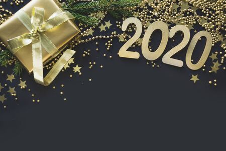 Happy New 2020 Year. Christmas border of golden gift box, decoration, shine stars and beads on black...
