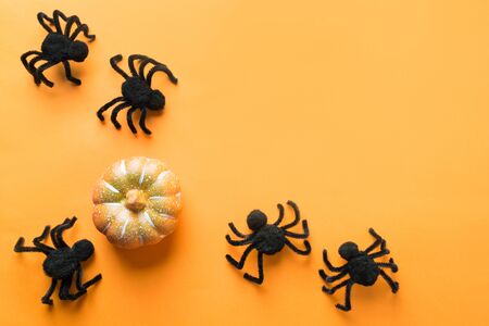 Halloween decorations with black spiders and pumpkin on orange background. Flat lay. View from above, copy space.の写真素材