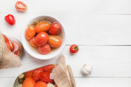 Canned vegetables tomato in glass jars on white wooden board. View from above. Various types of canned. Homemade harvest fall preparations.の写真素材