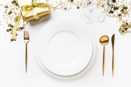 Christmas table setting with golden dishware, silverware and party decorations on white background. Top view. Xmas dinner.の写真素材