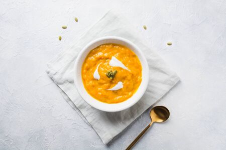 Autumn pumpkin and carrot soup with cream on grey stone background. View from above and space for text.の写真素材